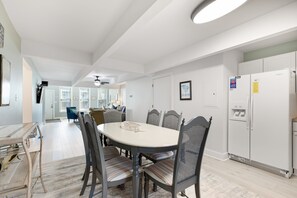 Una cocina moderna con un refrigerador blanco, una mesa de comedor con sillas y un ventilador de techo.