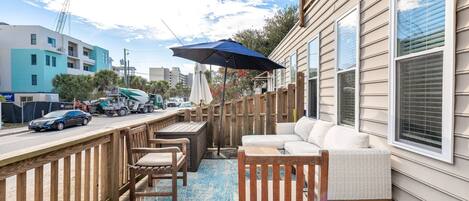 A wooden deck with outdoor furniture, a blue rug, and a large umbrella.