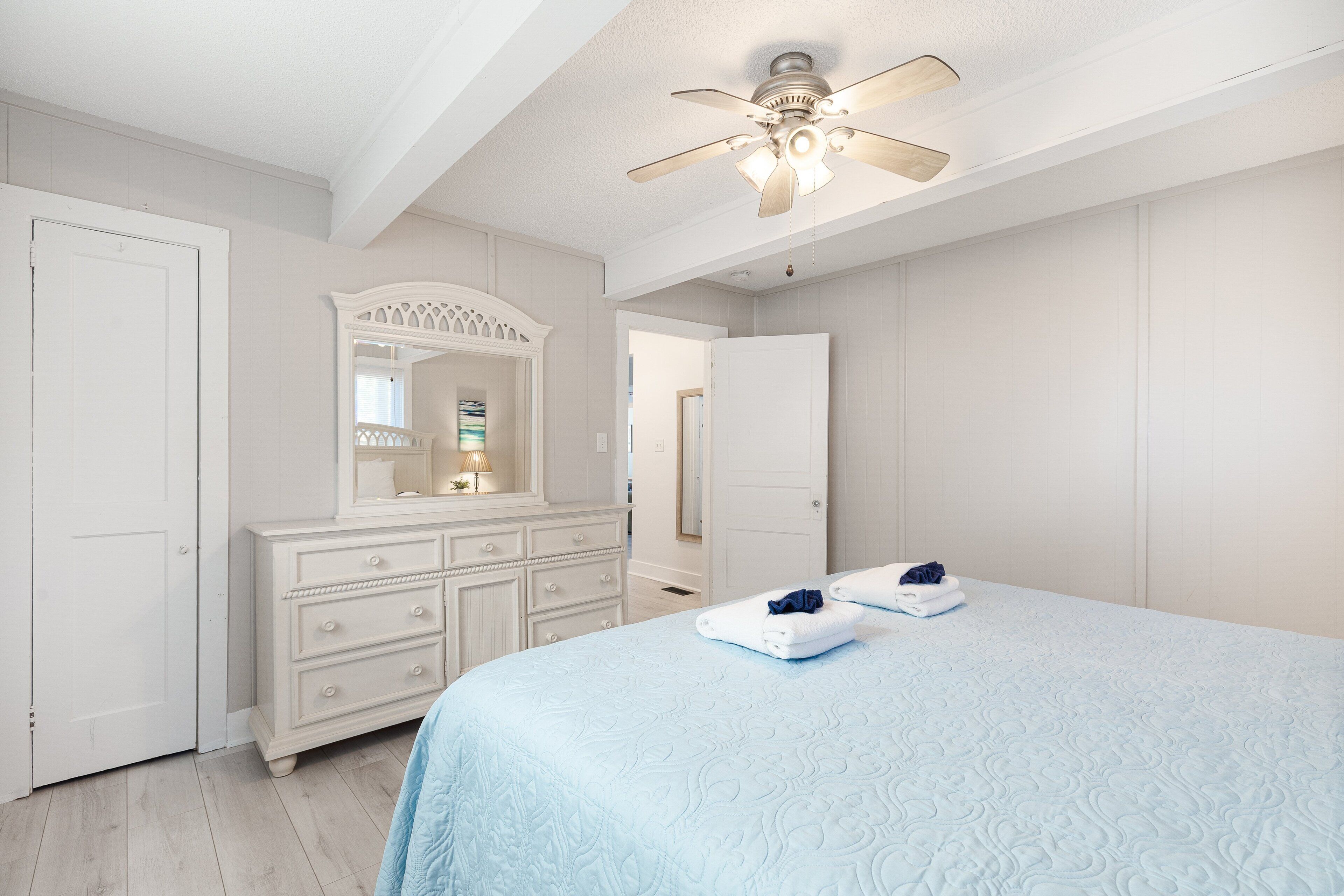 A bedroom with a bed, dresser, and ceiling fan.