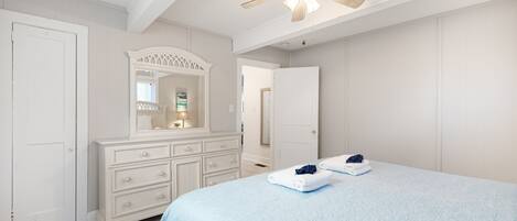A bedroom with a bed, dresser, and ceiling fan.