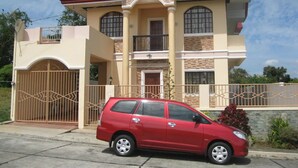 A two-story house with a red car parked in front.