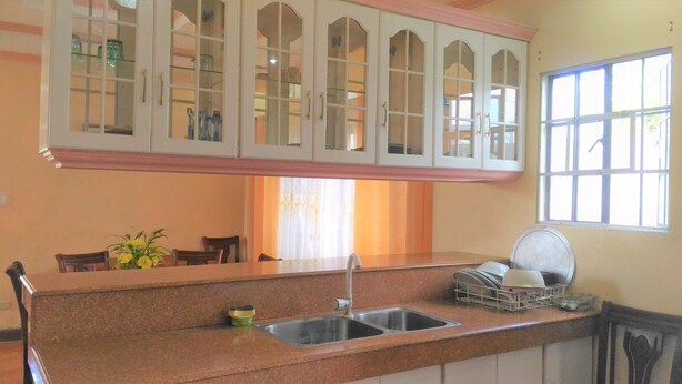 A kitchen with a granite countertop, a sink, and a window with blinds.