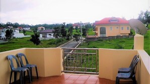 A balcony with a view of a residential area, a satellite dish, and two chairs.