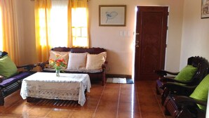 A living room with a sofa, a coffee table with a vase of flowers, and a wooden door.