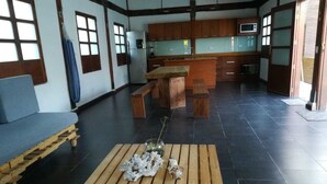 Amplia sala de estar con un banco de madera, un sofá y una cocina al fondo.
