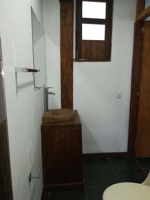 A bathroom with a wooden sink, a mirror, a window, and a door.