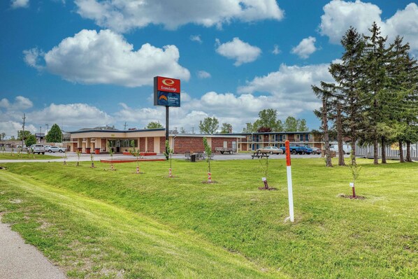 A hotel with a large sign for Econo Lodge, a parking lot, and a grassy area with trees.