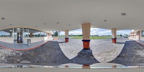 A modern building with a curved roof, large pillars, and a glass entrance.