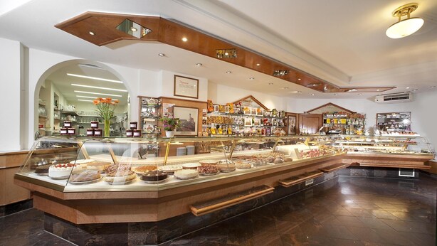 A bakery counter with various baked goods, a wooden ceiling, and a marble floor. - Hotel Greinwald (Marktoberdorf)