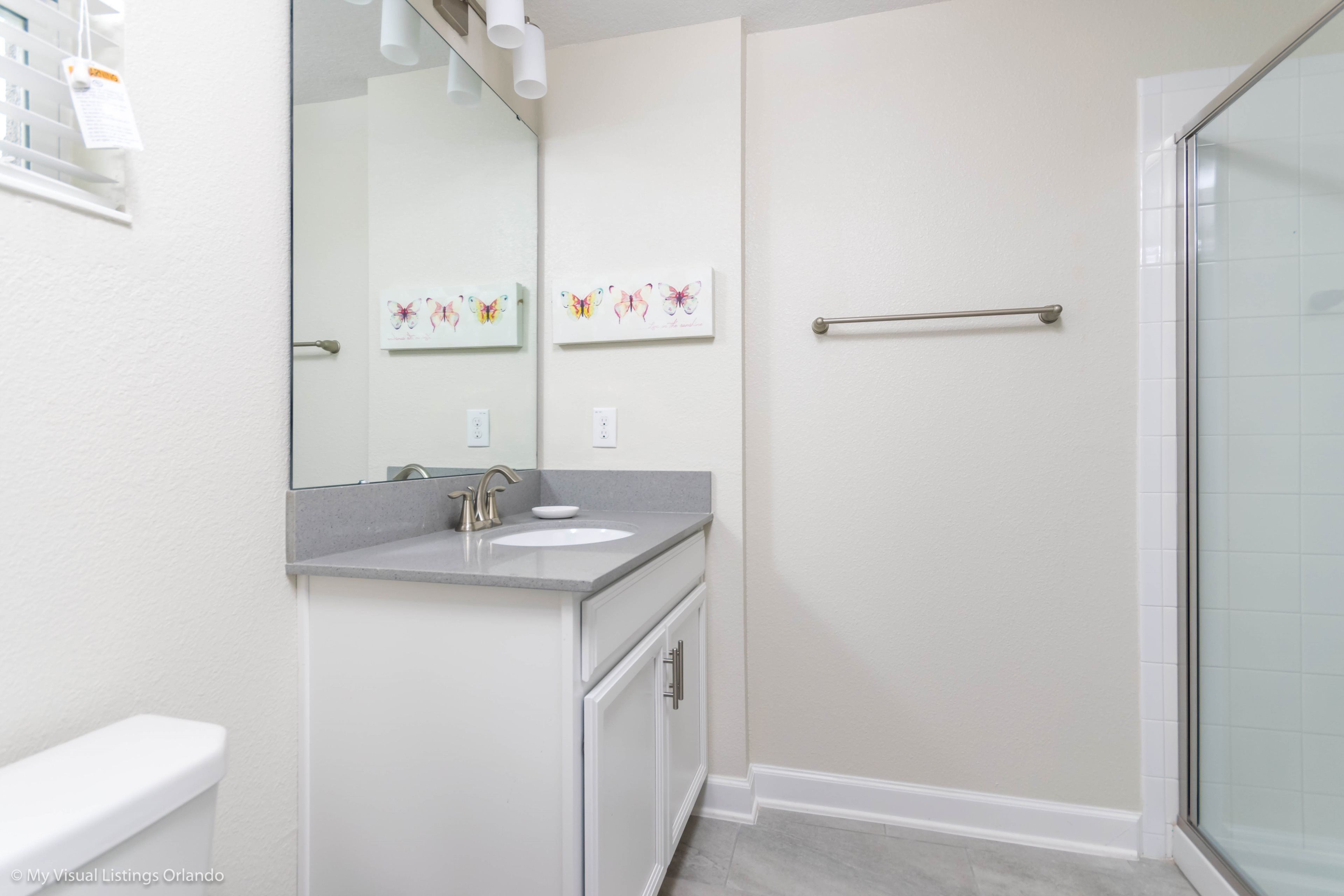 Une salle de bain avec des toilettes blanches, un lavabo avec un miroir et une douche en verre.