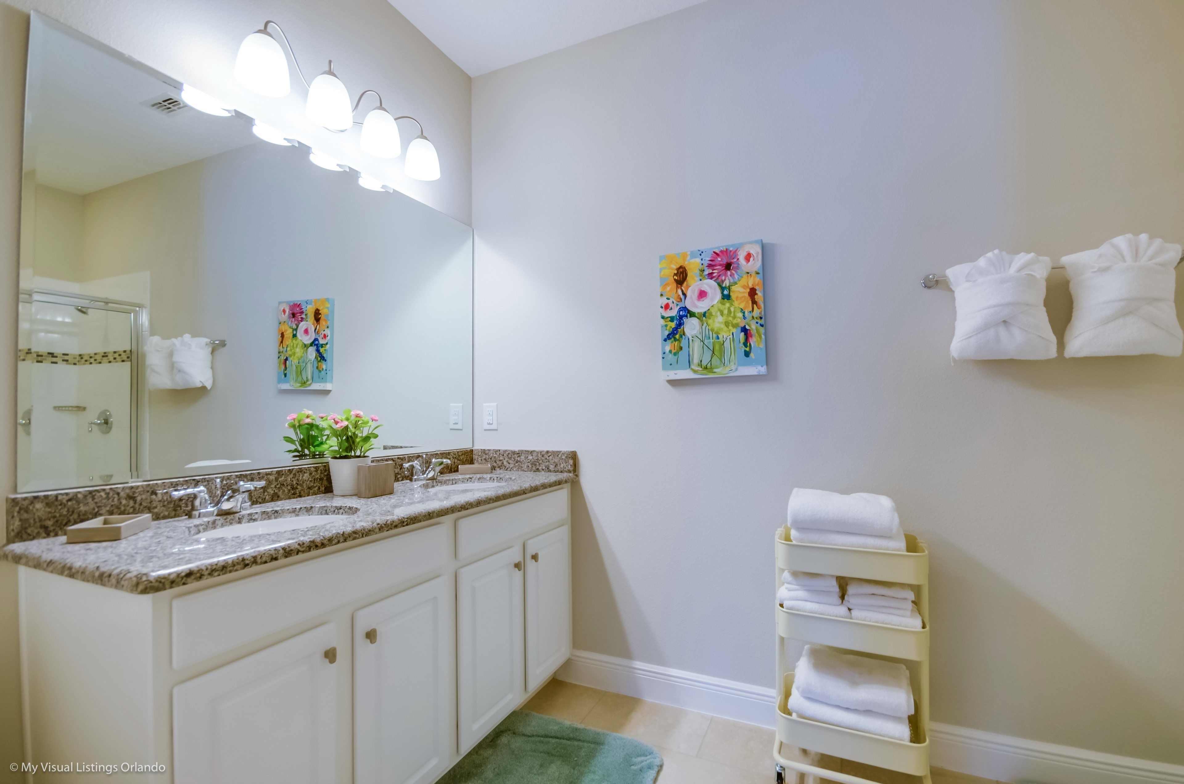 Une salle de bain avec un double lavabo, un grand miroir et un porte-serviettes.