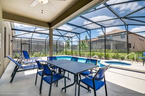 A covered outdoor area with a pool, blue chairs, and a table. - H5287 Ultimate 5 Bedroom 5 Bathroom Luxury Villa (Davenport)