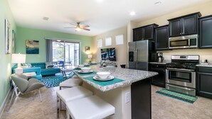 A modern kitchen with dark cabinets, stainless steel appliances, and a teal backsplash. - H5287 Ultimate 5 Bedroom 5 Bathroom Luxury Villa (Davenport)