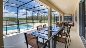 Ett rymligt inomhusomrÄde med ett glastak, en pool och en matplats med stolar och bord.