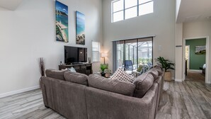 A spacious living room with a large sectional sofa, a flat-screen TV, and artwork on the walls. - H5424 Ultimate 5 Bedroom 5 Bathroom Luxury Villa (Davenport)