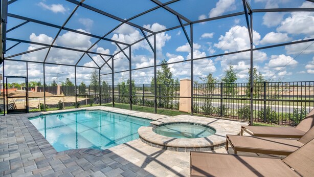 A covered outdoor swimming pool with lounge chairs and a hot tub.