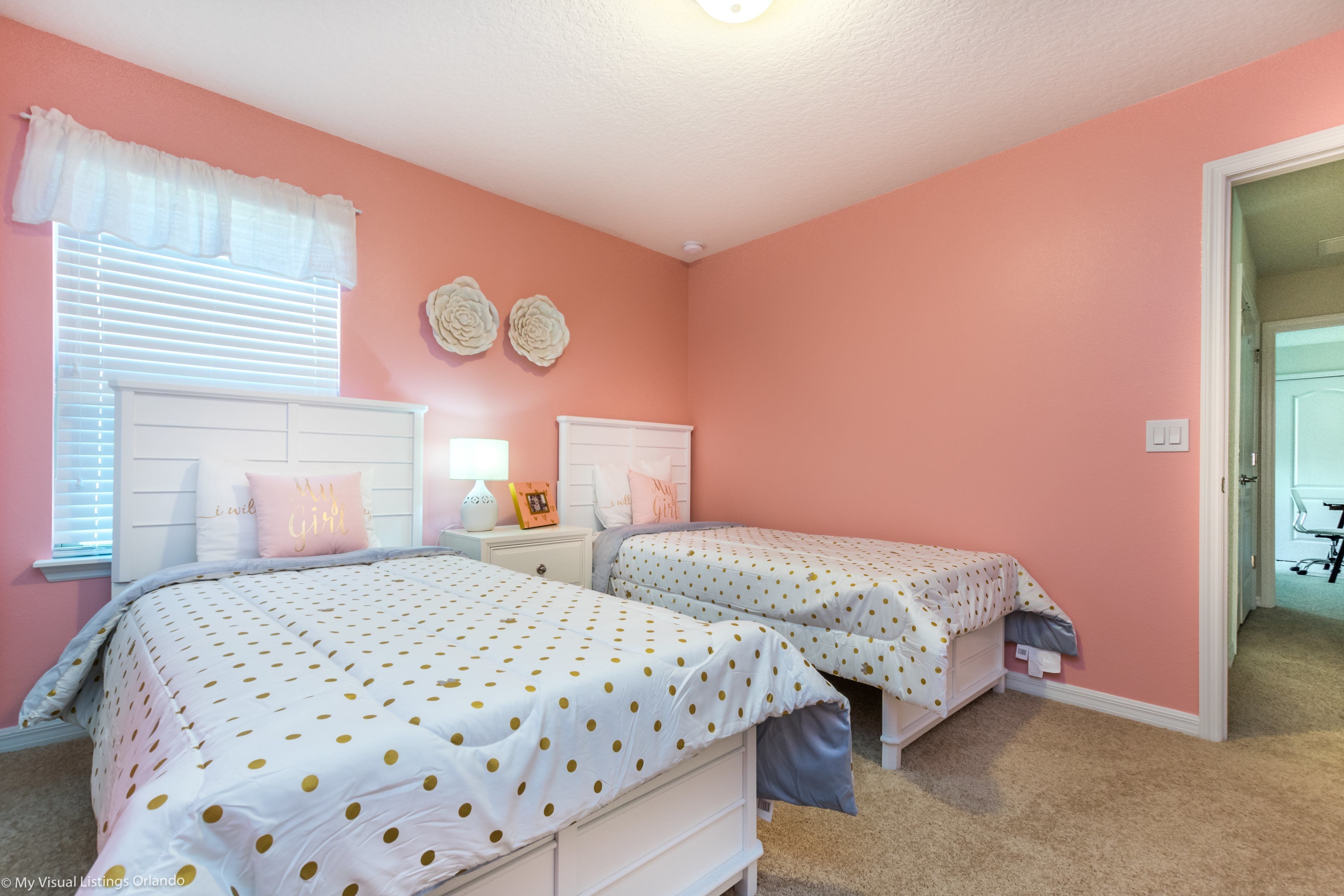 A bedroom with two beds, a nightstand, and a window with blinds.