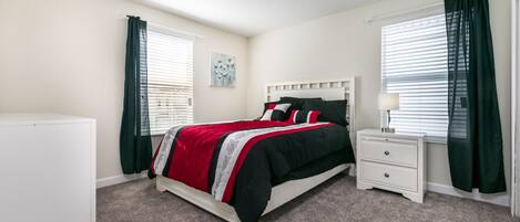 Un dormitorio con cama, mesita de noche, cómoda y ventana con cortinas.