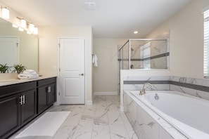 A modern bathroom with a large bathtub, a vanity with dark cabinets, and a mirror with lights above. - H1596 Brand new Amazing 6 Bedroom 6 Bathroom Fiji (Davenport)