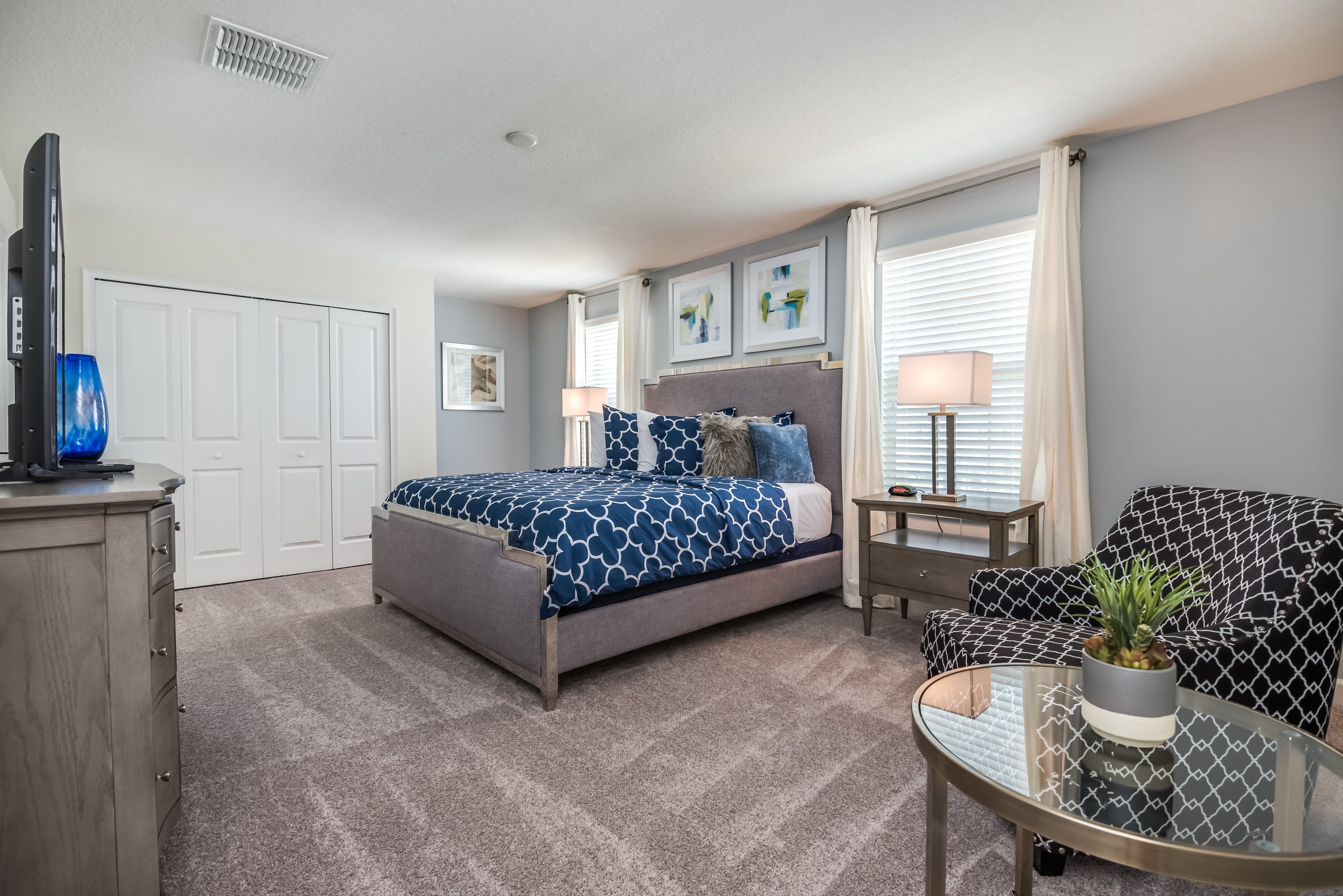 A bedroom with a bed, bedside tables, a TV, a sofa, and a window with curtains.