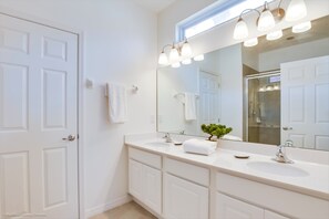 Un baño moderno con un espejo grande, dos lavamanos y una pequeña planta en maceta.
