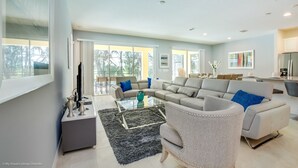 Ein modernes Wohnzimmer mit einer Eckcouch, einem Glastisch und einem grauen Sessel.