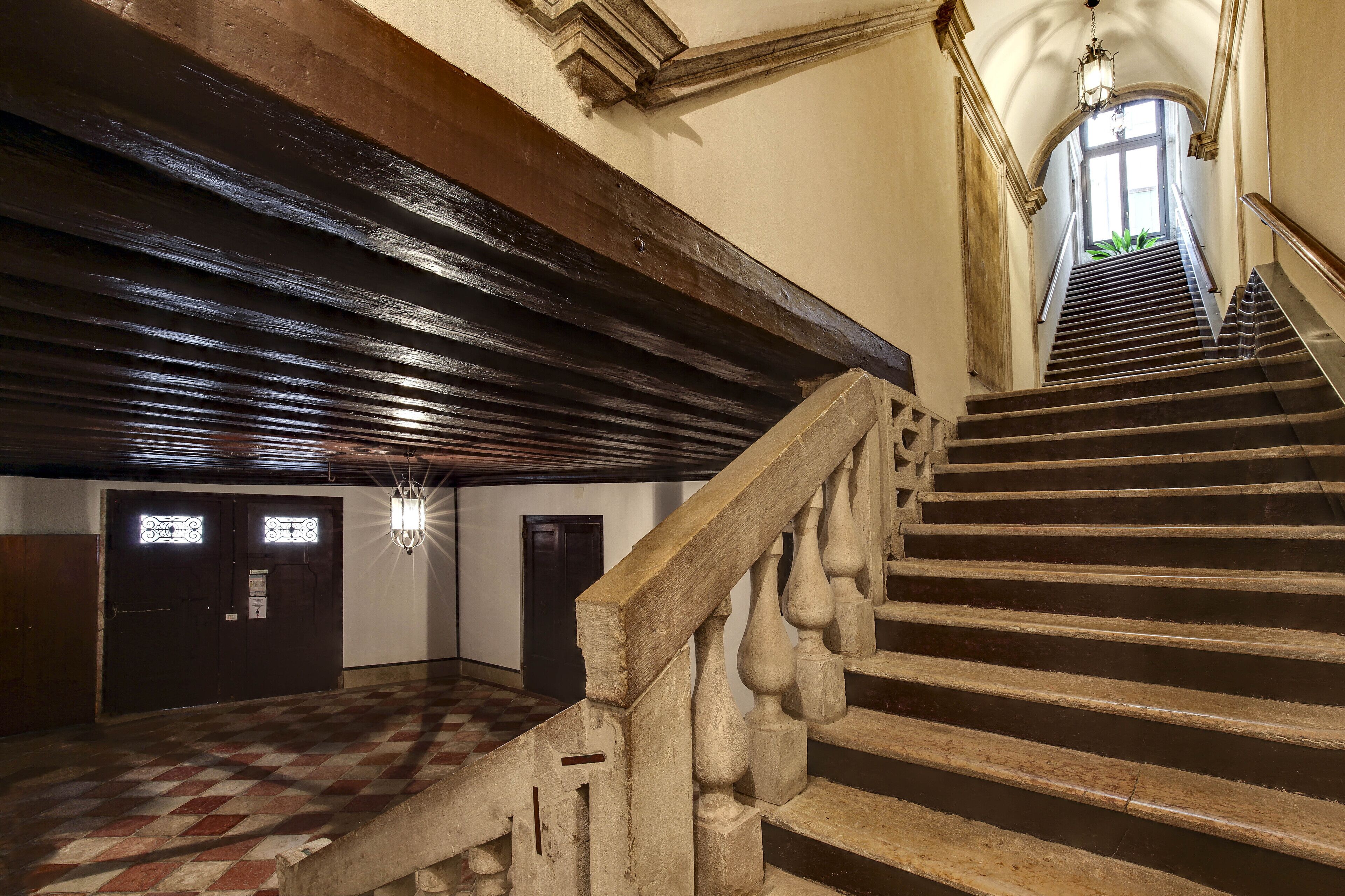 Eine imposante Treppe mit Schachbrettmuster führt zu einer Tür mit Fenster.