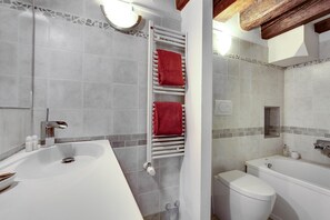 A bathroom with a white bathtub, a white toilet, and a shower area.