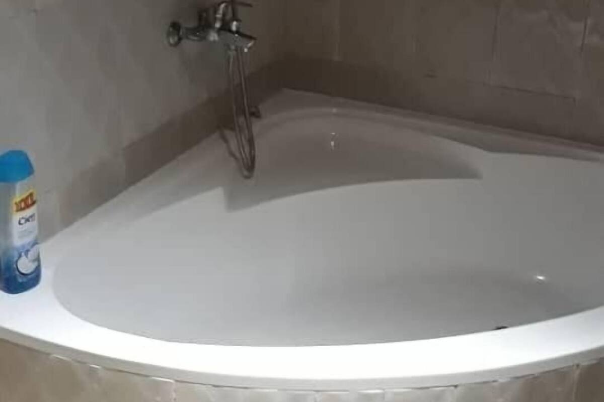 Une salle de bain avec une baignoire, une douche et une fenêtre avec un rideau.