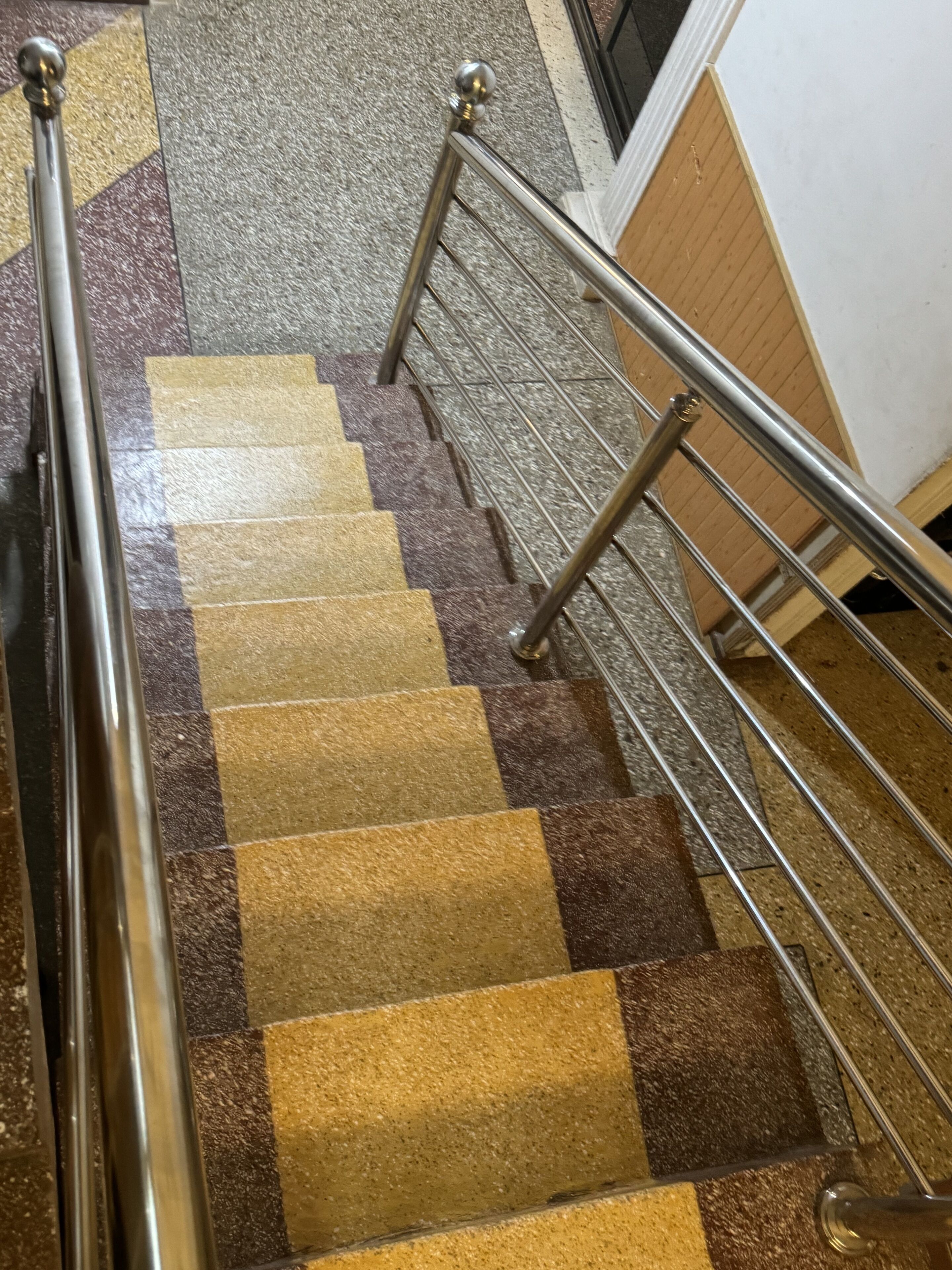 Uma escadaria com padrão de piso quadriculado e corrimãos de metal.