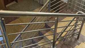 Un escalier avec des rampes en métal, une moquette à motifs et une porte avec une pancarte.