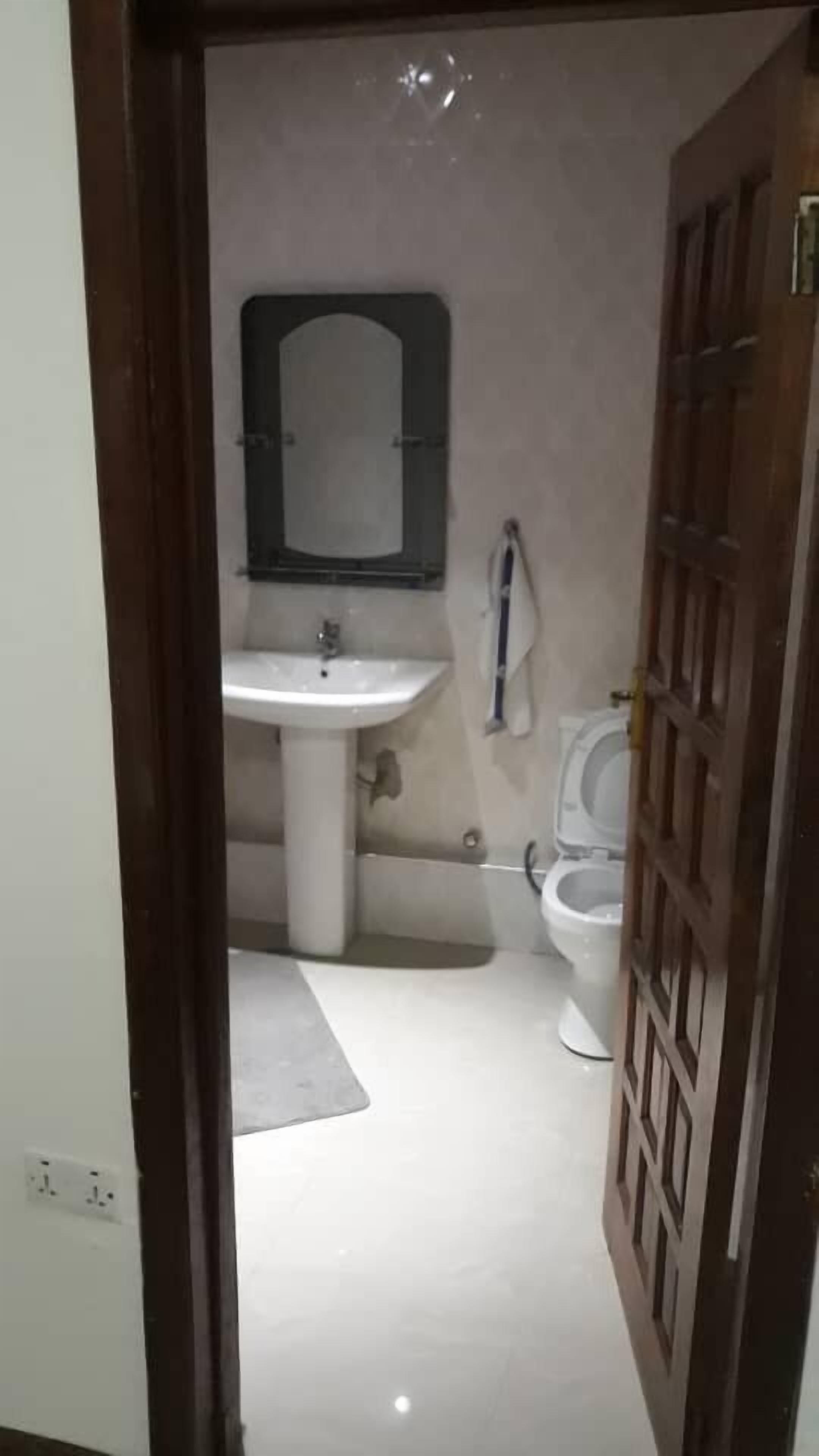A small bathroom with a sink, mirror, and toilet.