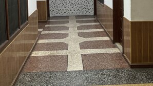 Un couloir aux murs ornés de motifs, doté d’un sol carrelé et de portes de part et d’autre.