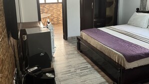 Une chambre à coucher comprenant un lit, une armoire, un bureau avec une chaise, une télévision et un ventilateur de plafond.