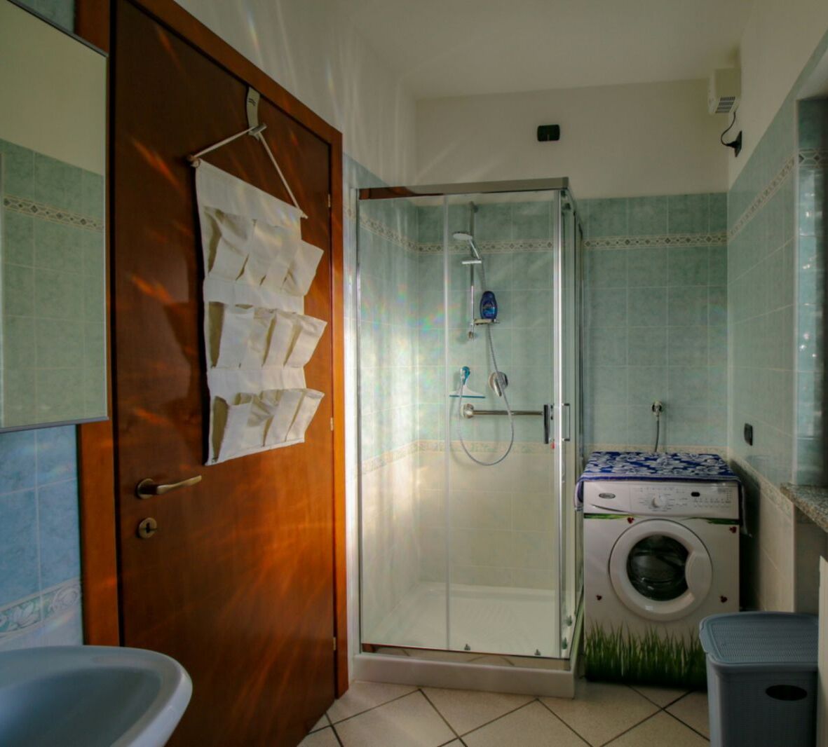 Ein Badezimmer mit Duschkabine, Waschmaschine und Waschbecken.