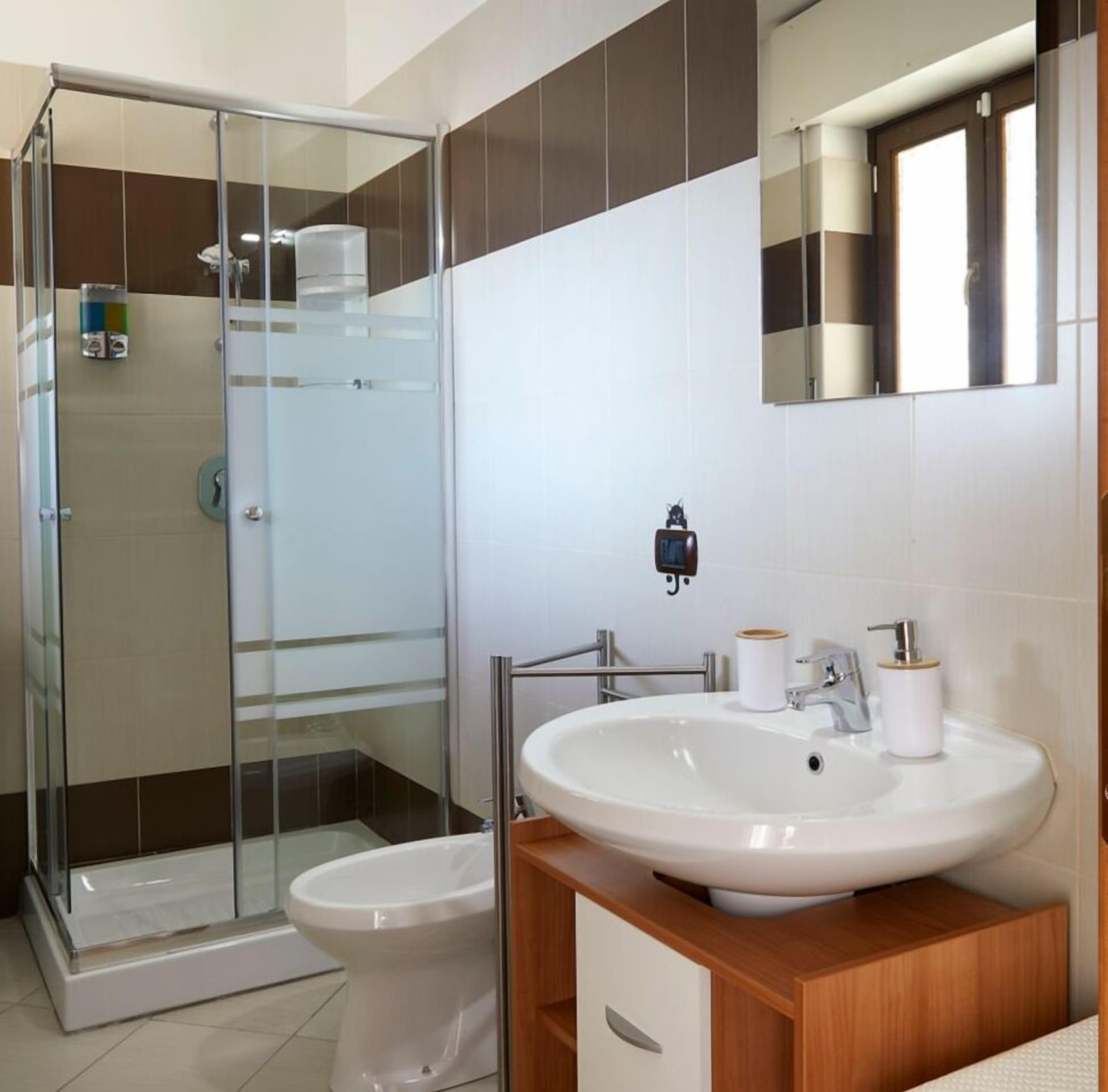Ein modernes Badezimmer mit Duschkabine aus Glas, Toilette, Waschbecken mit Spiegel und Toilettenpapierhalter.