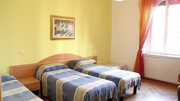 A room with two single beds, a wooden headboard, a nightstand, a framed picture on the wall, and a window with curtains. - B&B Citta Studi (Milan)