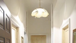 A hallway with a wooden door at the end, a yellow carpet, and a wooden dresser to the right. - B&B Citta Studi (Milan)
