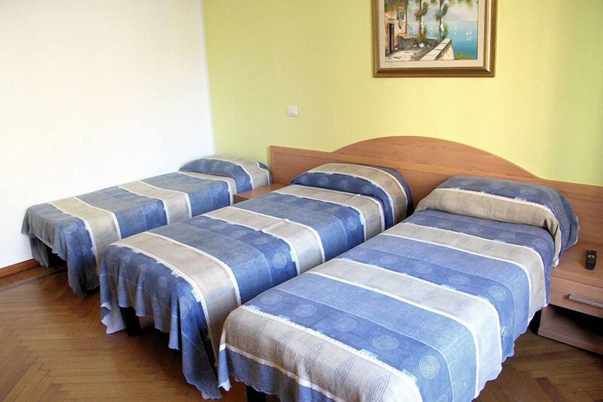 A room with three single beds, each with a blue and white striped bedspread.