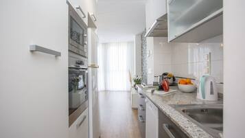 Una cocina moderna con muebles blancos, electrodomésticos de acero inoxidable y encimera de granito.