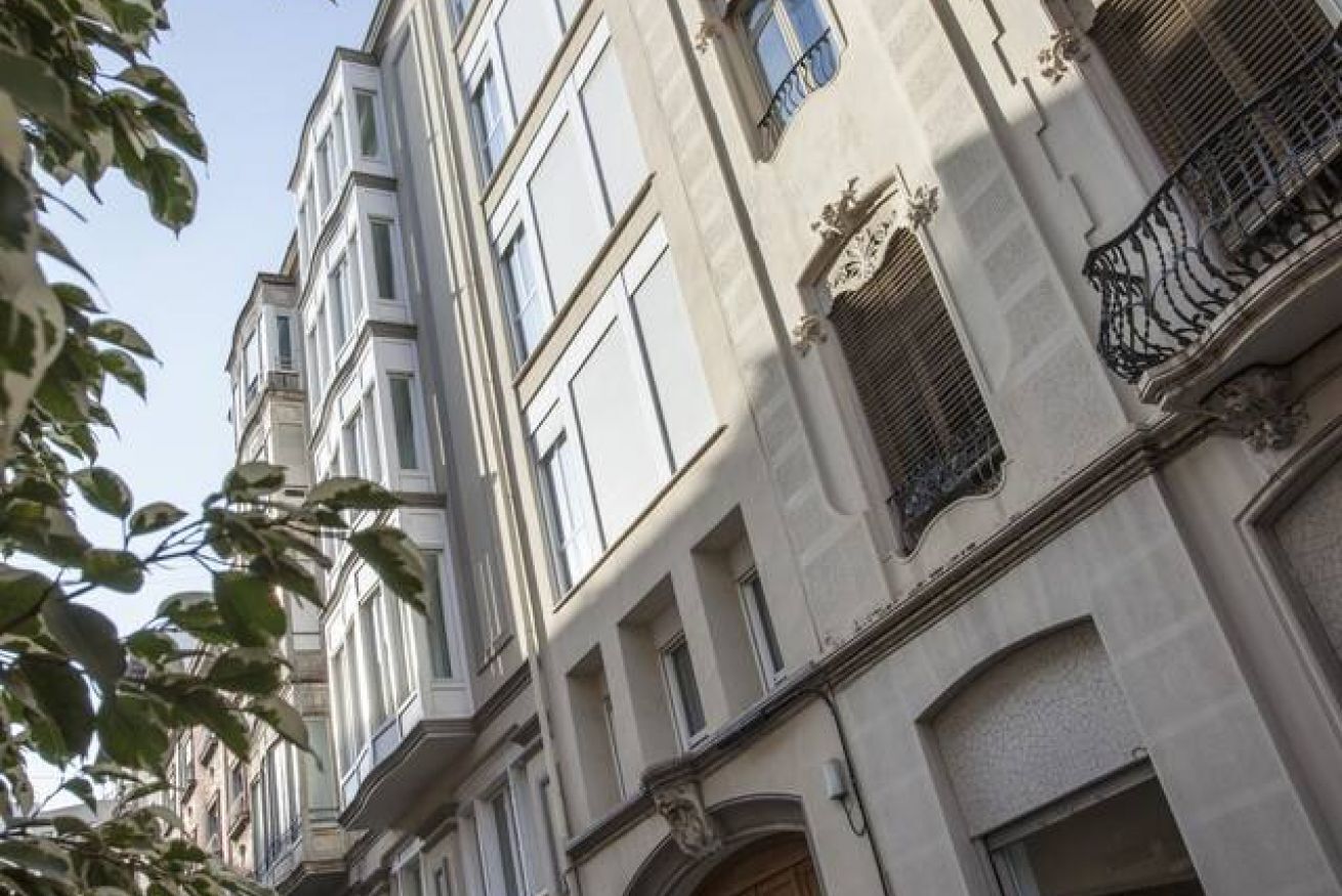 Un edificio de varios pisos con arquitectura clásica, que presenta ventanas simétricas y detalles ornamentales.
