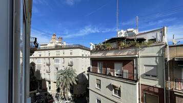 Un edificio de varios pisos con balcones, una palmera y un cielo azul despejado.