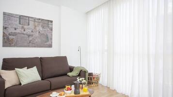 Una sala de estar moderna con un sofá marrón, una mesa de centro con alimentos para el desayuno, una cesta y un cuadro en la pared.