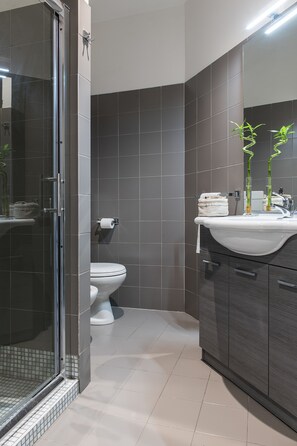 A modern bathroom with a glass shower enclosure, a white toilet, and a sink with a mirror.
