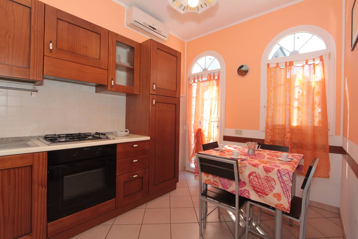 A kitchen with wooden cabinets, a gas stove, and a dining area with a table and chairs.