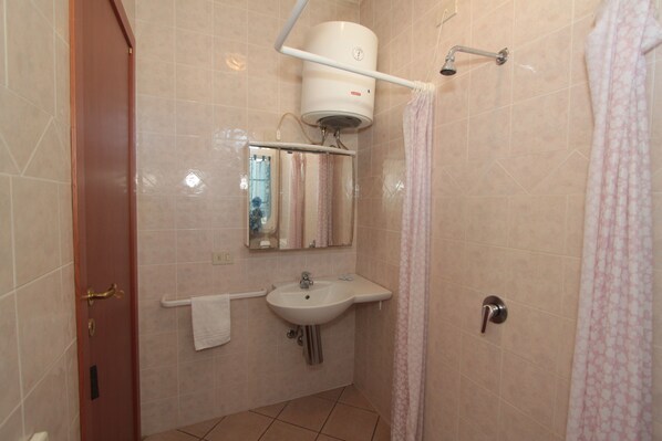 A bathroom with a sink, mirror, towel rack, shower curtain, and a door.