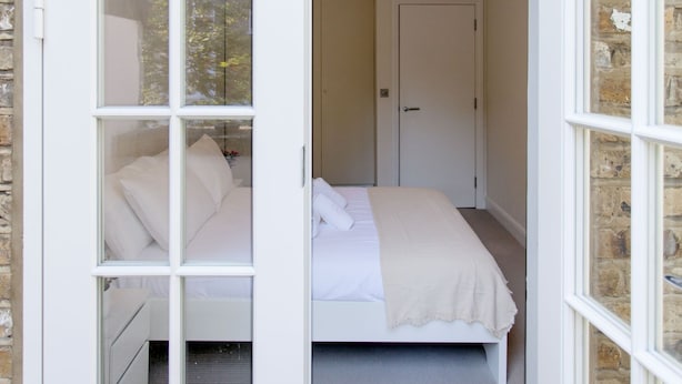 A bedroom with a bed, a door, and a window. - Chelsea Residential Atmosphere (London)
