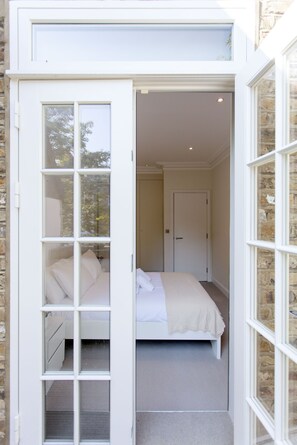 A bedroom with a bed, a door, and a window. - Chelsea Residential Atmosphere (London)