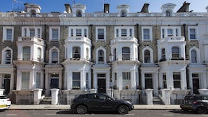 A row of Victorian-style terraced houses with white facades, multiple windows, and small balconies. - Chelsea Residential Atmosphere (London)