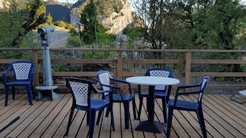 An outdoor deck with wooden flooring, blue and white chairs, and a small round table.